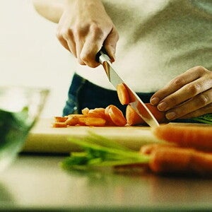 Mujer cortando zanahorias con ácido fólico.