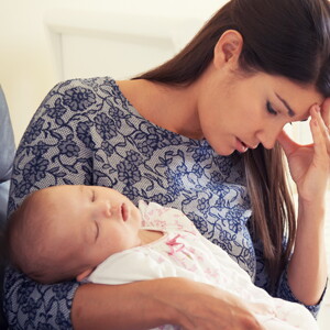 Mujer con depresión posparto cansada y sosteniendo a su bebé. 