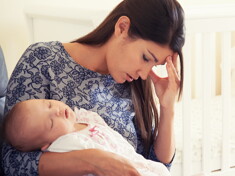 Entendiendo la depresión posparto Mujer con depresión posparto cansada y sosteniendo a su bebé.