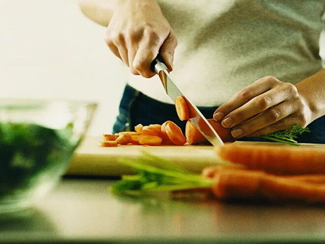 Mujer cortando zanahorias con ácido fólico.