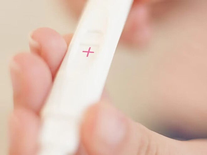 Manos sosteniendo test de embarazo positivo